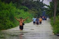 Thai family people natural disaster victims walking wading in water on street of alley while water flood road go receive goods