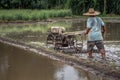Thai farmer driving tiller tractor to plow paddy field before rice culture, Chiang Mai, Thailand