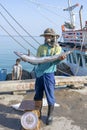 Thai fisherman shows caught fish on the pier near fishing boat on the island Koh Phangan, Thailand