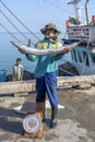 Thai fisherman shows caught fish on the pier near fishing boat on the island Koh Phangan, Thailand