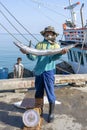 Thai fisherman shows caught fish on the pier near fishing boat on the island Koh Phangan, Thailand Royalty Free Stock Photo