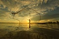 Thai fisherman on wooden boat casting a net