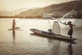 Thai fisherman on wooden boat casting a net for catching freshwater fish in nature riverThai fisherman on wooden boat casting a ne Royalty Free Stock Photo