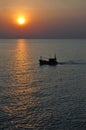 Thai fishing boat passes by the sun as it sets on Hua Hin coast Royalty Free Stock Photo