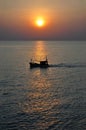 Thai fishing boat passes by the sun as it sets on Hua Hin coast Royalty Free Stock Photo