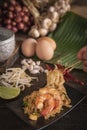 Thai fried noodles or pad thai with shrimp on black plate placed on the wood table there are eggs, garlic, bean sprouts, shallot, Royalty Free Stock Photo