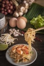 Thai fried noodles or pad thai with shrimp on white plate placed on the wood table there are eggs, garlic, bean sprouts, shallot, Royalty Free Stock Photo