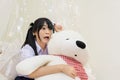 Thai high school girl in glasses show shocking expression while hugging teddy bear