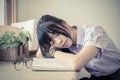 Thai high school girl in uniform fall asleep on the book on her desk during doing homework Royalty Free Stock Photo