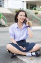 Thai high schoolgirl student in school uniform sit and chat on mobile Royalty Free Stock Photo