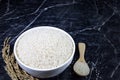 Thai jasmine rice broken rice in white ceramic bowl and wooden spoon on dark marble table Royalty Free Stock Photo