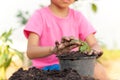 Thai kid girl wearing pink shirts planting trees. She was using her hands to put the black soil into the black pot. to grow tree s Royalty Free Stock Photo