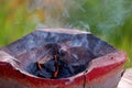 An old style brazier with hot coal and smoke in outdoor, blurred green nature background Royalty Free Stock Photo