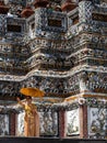 Thai lady dressed in traditional orange clothes and a sun umbrella is standing by the Wat Arun Temple, Temple of Dawn, in Bangkok