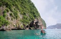 Thai long tail boat and unidentified tourists snorkel near the entrance at the Viking Cave of Phi Phi Ley Island, Thailand