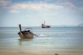 Thai longtail boat on the beach of Phra Nang. Going to the sea, on background of a black sailing ship with red sails