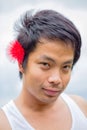 Thai man in white tank top put a red flower at his ear Royalty Free Stock Photo