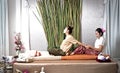 Thai Masseuse doing massage for woman in spa salon. Asian beautiful woman getting thai herbal massage compress massage in spa.She Royalty Free Stock Photo