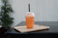 Thai milk tea frappe in takeaway cup on wooden table Royalty Free Stock Photo