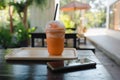 Thai milk tea frappe in takeaway cup served with wooden tray  near mobile phone Royalty Free Stock Photo