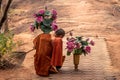 Thai monk with lotus flowers in his hands and traditional broom