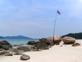 Thai national flag on rocks at blue sea white sand beach on Monkey island travel place near Lipe island