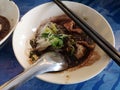 Thai Noodle, small noodles with pork stewed pork, meatball, pork liver and blood soup in white bowl, wooden chopsticks and spoon, Royalty Free Stock Photo