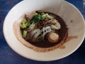 Thai Noodle, small noodles with pork stewed pork, meatball, pork liver and blood soup in white bowl, wooden chopsticks and spoon, Royalty Free Stock Photo