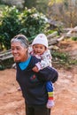 Thai northern grandma wearing long sleeve shirt and carry a child on her back in the Akha village of Maejantai on the hill. Royalty Free Stock Photo