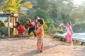 Thai northern kid wearing pyjamas standing with sunlight and her friends in the background in the Akha village of Maejantai.