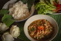 Thai Northern Style Pork and Tomato Chili Relish, nam prik ong in white bowl on wood table there are side dishes of fresh
