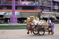 Thai old man and senior woman keep pickup trash recyclable waste garbage and push cart bicycle on street with traffic road at