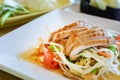 Thai papaya salad on white dish with grilled pork