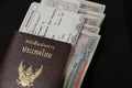Thai passport with boarding pass and Kyat money of Myanmar on black floor.