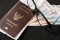 Thai passport with boarding pass, Kyat money of Myanmar and eyeglasses on black floor.