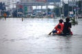 Thai people natural disaster victims use vessel wading in water on street of alley while water flood road wait help rescue and