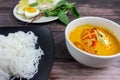 Thai rice noodles in grab curry sauce with vegetable and boiled eggs on wood table Royalty Free Stock Photo