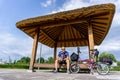 Thai skinhead cyclist sits under the Korean traditional pavilion and holds Korea bicycle passport in his hand with folding bike Royalty Free Stock Photo