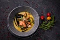 Thai soup with seafood, shrimp, salmon. Served in a gray deep stone plate