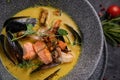 Thai soup with seafood, shrimp, salmon. Served in a gray deep stone plate