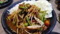 Thai spicy seafood papaya salad with salted crab and fermented fish mixed with white rice noodle on black dish