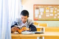 A thai student in sweater is learning with his dictionary in Thai classroom of Wantamaria school Pranburi, Thailand February 6,