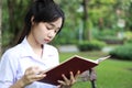 Thai student teen beautiful girl read a book sitting in park. Royalty Free Stock Photo