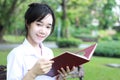 Thai student teen beautiful girl read a book sitting in park. Royalty Free Stock Photo