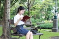 Thai student teen beautiful girl read a book sitting in park. Royalty Free Stock Photo