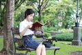 Thai student teen beautiful girl read a book sitting in park. Royalty Free Stock Photo