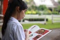 Thai student teen beautiful girl read a book sitting in park. Royalty Free Stock Photo