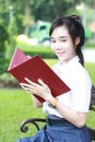 Thai student teen beautiful girl read a book sitting in park. Royalty Free Stock Photo