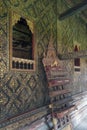 Thai-style decorated window and gilded wall, with scripture box on carved wooden shelf at Wat Mahathat Temple