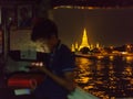 Thai teenager sails by boat along the Chaopraya River near Wat Arun